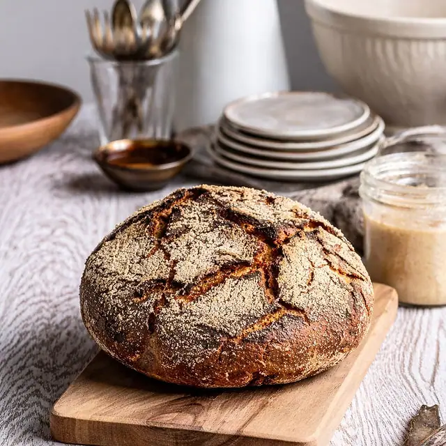 A dark rye loaf, cut open, on a wooden board