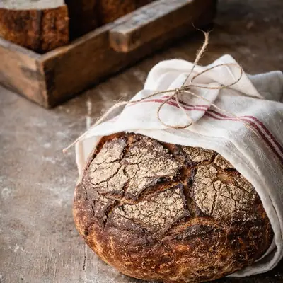 Signature Rye Loaf, wrapped in a linen cloth on a floured board