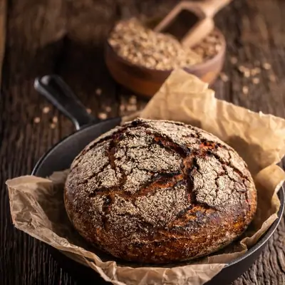 Sunshine Rye Loaf in a cast iron pan, sunflower seeds beside it